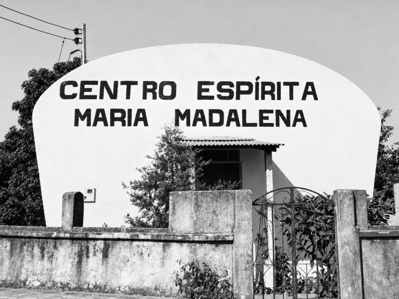 Fachada em arco com o nome Centro Espírita Maria Madalena pintado na parede branca.