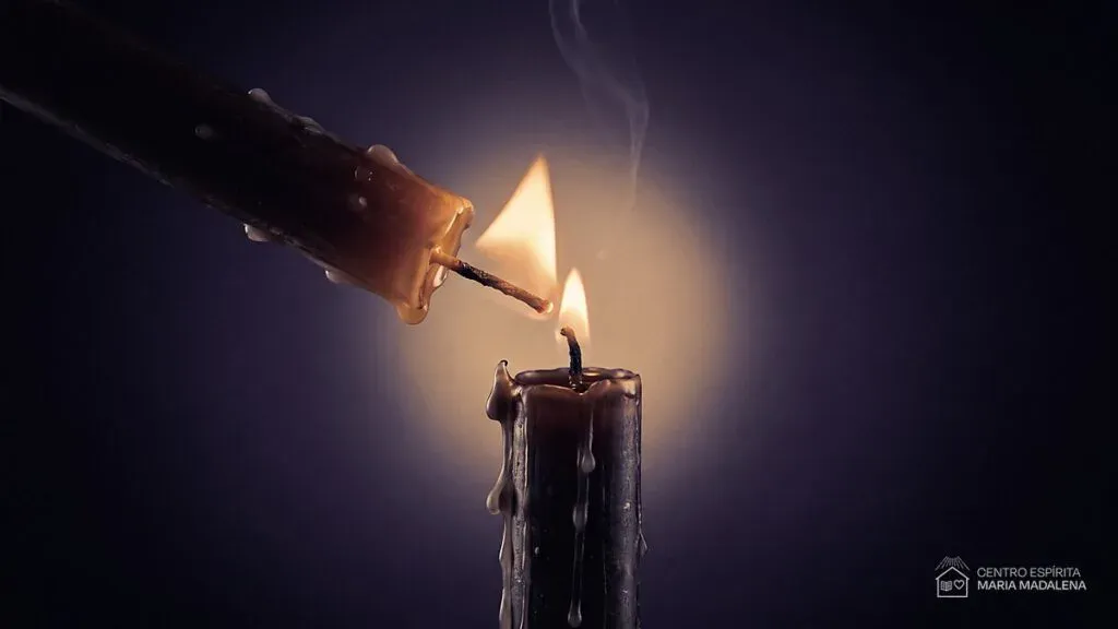 Vela acesa inclinada acendendo o pavio de outra vela, símbolo da luz que se transmite