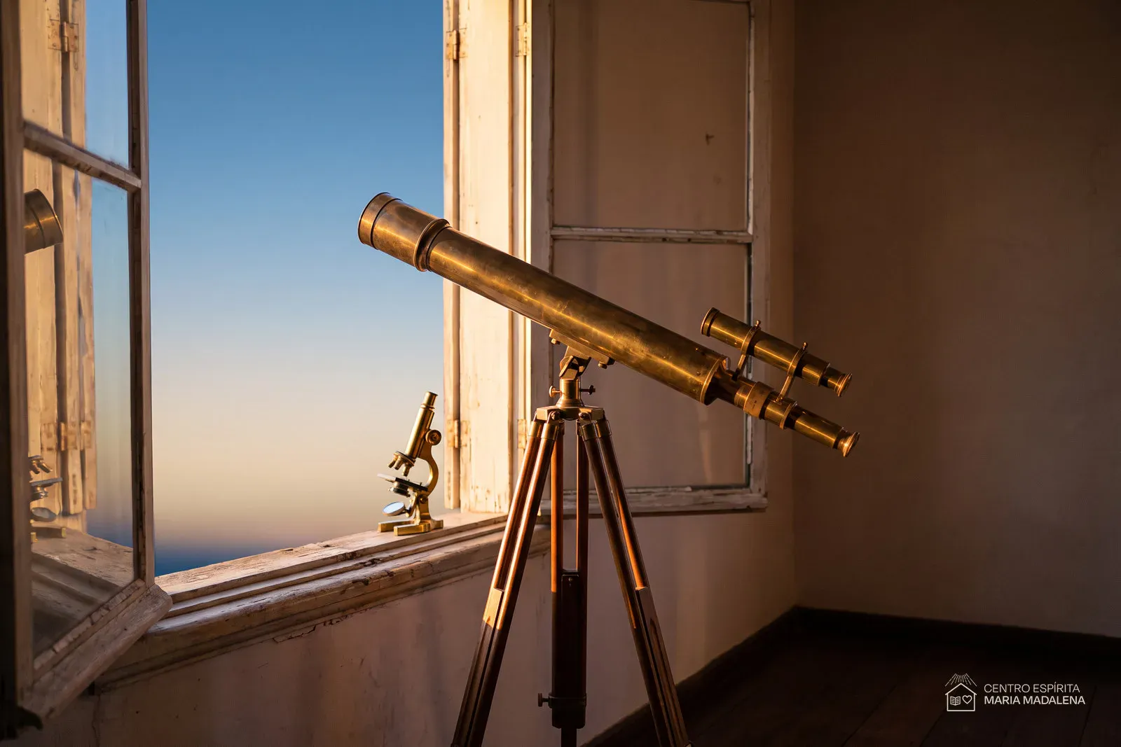 Telescópio de latão antigo e um pequeno microscópio junto a uma janela aberta ao entardecer