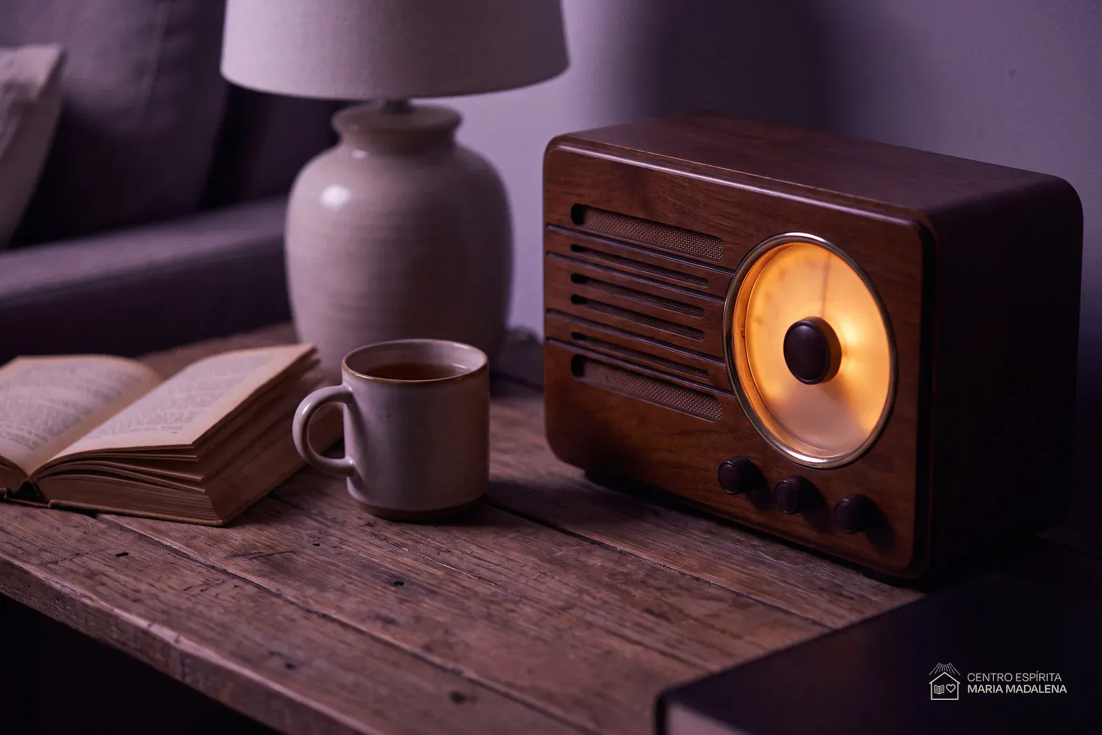 Rádio antigo de madeira ligado sobre a mesa da sala, com o mostrador aceso em luz âmbar